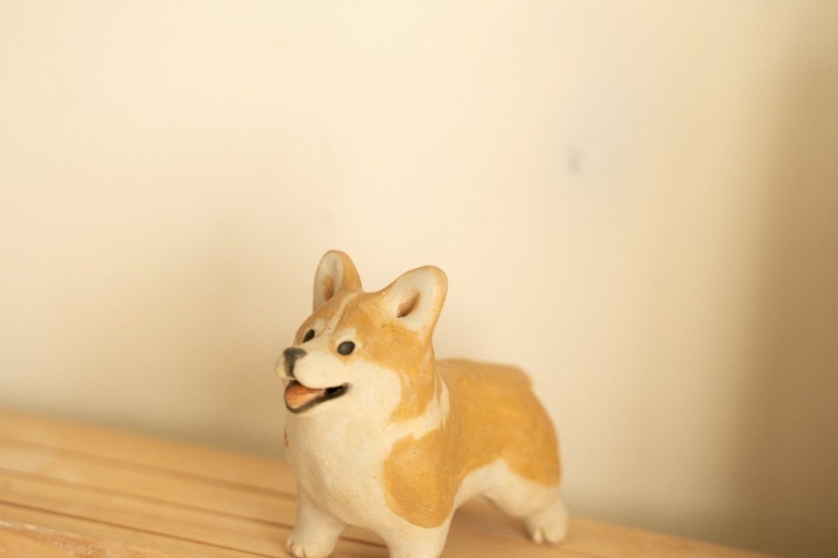 Hand-painted miniature Corgi dog pottery doll with custom pudding accessory. Artisan ceramic pet portrait figurine from a Singapore studio.